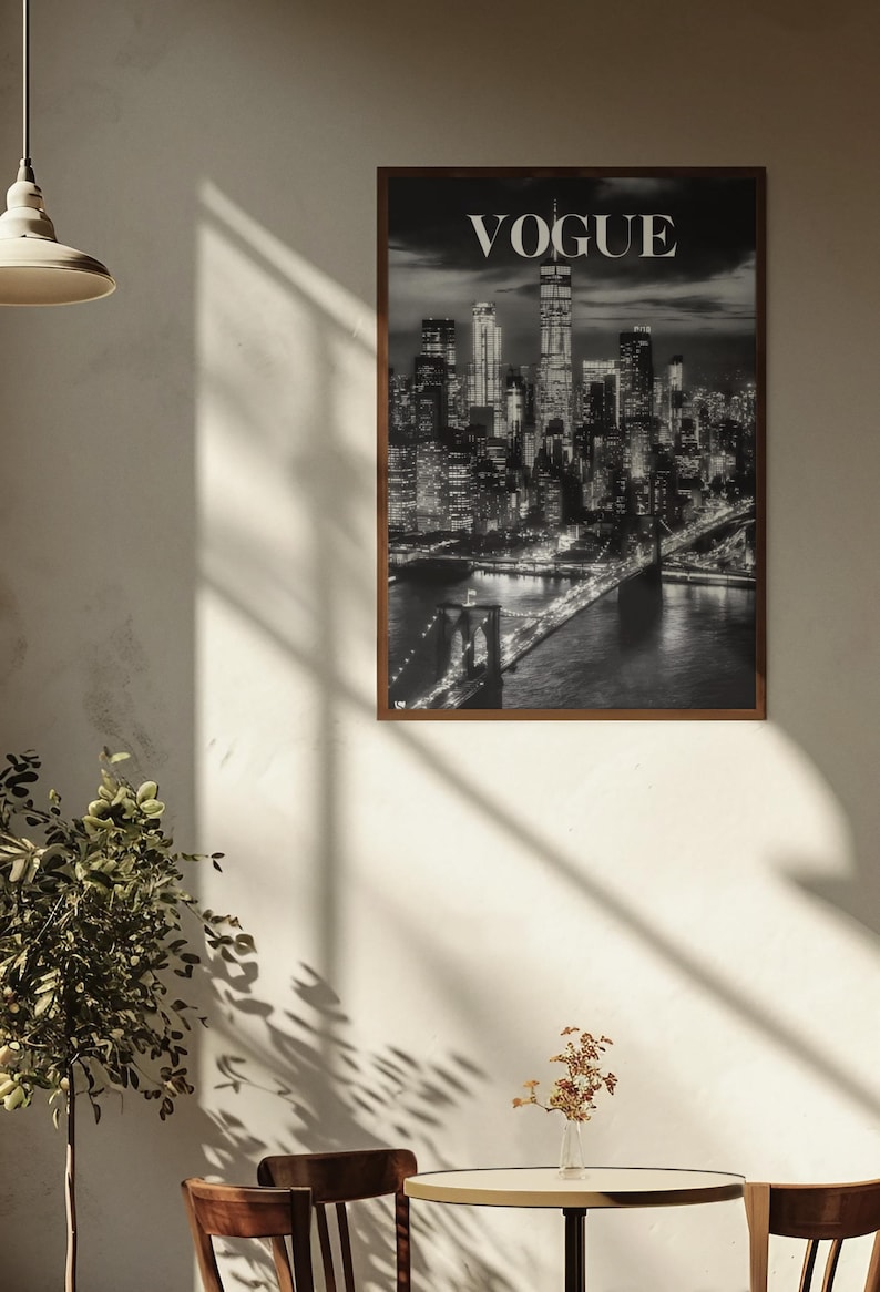 May include: A rectangular wall art print featuring a black and white night cityscape of New York City, including the Brooklyn Bridge and the Manhattan skyline, with the word VOGUE printed in white capital letters at the top center of the image.