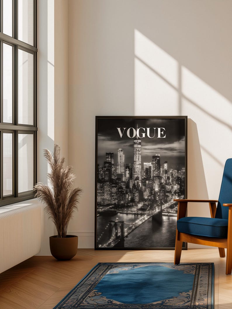 May include: A framed black and white wall art print featuring a nighttime cityscape of New York City with the Brooklyn Bridge in the foreground and the word VOGUE printed in white capital letters at the top center of the composition.