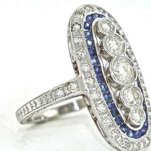 May include: A silver ring with a row of blue sapphires and a cluster of round diamonds set in an oval shape.