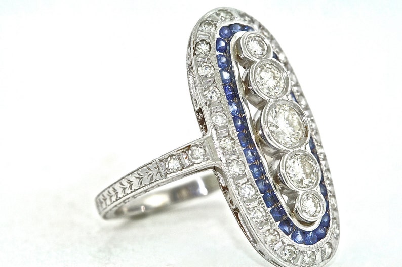May include: A silver ring with a row of blue sapphires and a cluster of round diamonds set in an oval shape.