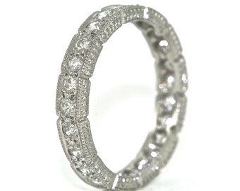 Könnte beinhalten: Ein silberner Ewigkeitsring mit einem zarten, filigranen Design, das mit kleinen Diamanten besetzt ist, die in einer durchgehenden Linie um den Ring verlaufen.