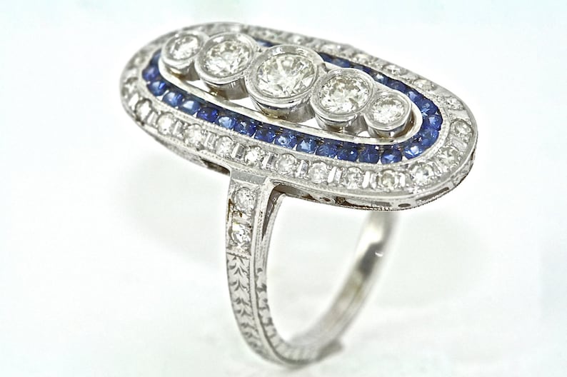 May include: A silver ring with a row of blue sapphires and a row of diamonds surrounding five larger diamonds in the center.