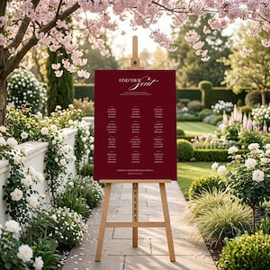 Puede incluir: Un cartel de distribución de asientos rectangular de color rojo intenso expuesto sobre un caballete de madera clara. El cartel presenta el texto blanco Find Your Seat en la parte superior, seguido de columnas de nombres de invitados y Thank You For Celebrating With Us.