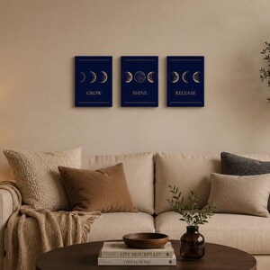Könnte beinhalten: Ein Set aus drei rechteckigen Wandbildern mit dunkelblauem Hintergrund und goldfarbenen Illustrationen der Mondphasen. Jeder Druck zeigt einen bestimmten Mondzyklus sowie die Wörter GROW, SHINE und RELEASE in einer klaren Schrift.