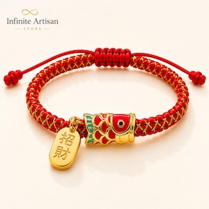 May include: A red braided cord bracelet featuring a gold-toned koi fish charm with red and teal enamel scales and a dangling gold-toned rectangular pendant engraved with the Chinese characters 招財, which translate to attracting wealth.