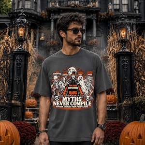 Puede incluir: Una camiseta gris carbón de manga corta con un estampado gráfico de un vampiro, un hombre lobo, un fantasma y una momia. El texto dice 404 PAGE NOT FOUND, NAME, MYTHS NEVER COMPILE y HORROR STORIES FROM PRODUCTION, con etiquetas para BUG FRANKENSTEIN, BSOD WEREWOLF, LOADING SPINNER GHOST y CRASHED SERVER MUMMY.