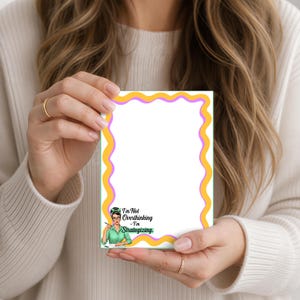 May include: A rectangular notepad with a white center and a wavy yellow and purple border. The bottom left corner features an illustration of a person with glasses and a green shirt, with the text I'm Not Overthinking - I'm Strategizing.
