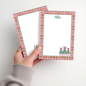 May include: Two rectangular note pads featuring a white center and a border of pink, green, and red plaid. The top pad displays the name Allie in green script, three illustrated Christmas trees with pink bows, and the text Merry & Bright.