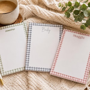 May include: Three rectangular paper notepads with white centers and gingham borders in sage green, grey, and dusty pink. Each notepad features a personalized name printed at the top: Jennifer in green, Bailey in black script, and Maggie in pink.