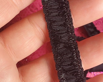 May include: Black elastic trim with a textured, ruffled design. The trim is approximately 1 inch wide.