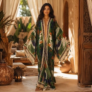 May include: A floor-length open-front kimono robe featuring a vibrant green base with a tropical botanical print of large leaves and colorful birds. The garment has wide, flowing sleeves and a cream-colored trim along the front edges.