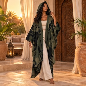 Peut inclure: Une cape à capuche ouverte sur le devant avec un imprimé géométrique abstrait vert olive foncé et noir. Le vêtement est porté sur un haut bustier beige clair et un pantalon large assorti, créant un ensemble superposé à la silhouette longue.