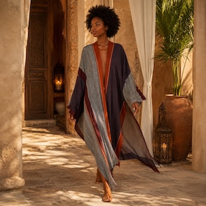 Könnte beinhalten: Ein langer, fließender Kimono-Mantel mit einem Color-Blocking-Design aus dunkelblauen Bahnen, einem feinen schwarz-weißen Mikromuster und einem kräftigen rostorangen Besatz entlang der offenen Vorderseite und der Ärmelkanten.