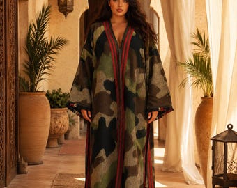 May include: A long, open-front duster coat featuring a camouflage pattern in shades of green, brown, and black. The garment has vertical red and black striped trim along the front opening and side slits, with frayed edges at the hem.