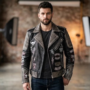 May include: A black leather motorcycle jacket featuring silver metal studs on the lapels and shoulders, adorned with various white and red graphic patches including lightning bolts, skulls, and text such as Ride Free and Rebel Soul.