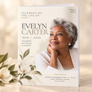 May include: A funeral programme booklet featuring a portrait of an older person with grey hair, the text Celebrating the Life of Evelyn Carter 1948-2026, and a floral illustration of white magnolia flowers with gold line accents on a cream background.