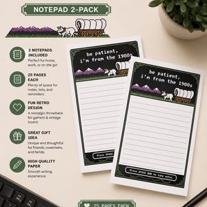 May include: A two-pack of white paper notepads featuring a pixelated graphic of a covered wagon and mountains. The text reads "be patient, i'm from the 1900s" and "Press SPACE BAR to take notes." Each notepad has lined pages and a dark green border.