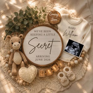 Könnte beinhalten: Ein Baby-Ankündigungsset mit einem runden Holzschild mit der Aufschrift WE'VE BEEN KEEPING A LITTLE Secret ARRIVING JUNE 2026, einem cremefarbenen, gerippten Langarm-Body mit BABY William, einem Ultraschallbild, einer Häkel-Giraffe und Holzblöcken.