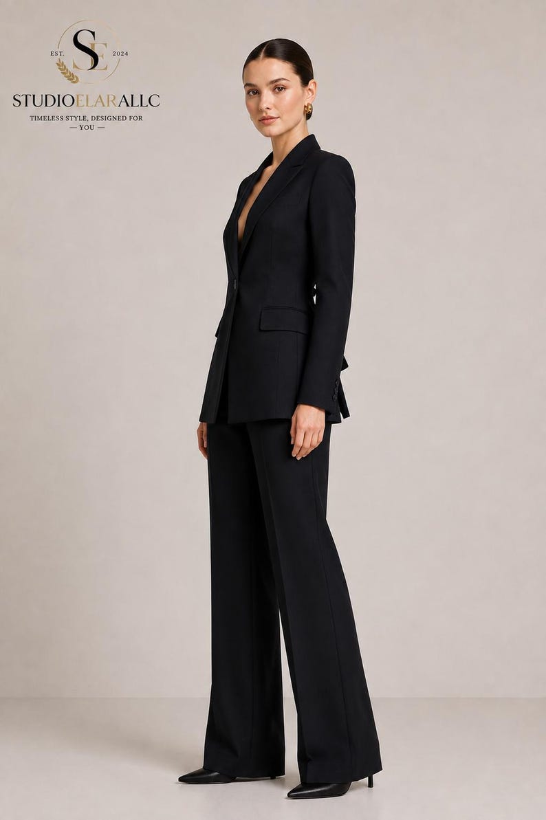 May include: A black tailored suit consisting of a single-button blazer with notched lapels and matching wide-leg trousers. The blazer features flap pockets and long sleeves. The logo STUDIOELARALLC EST. 2024 TIMELESS STYLE, DESIGNED FOR YOU is visible.