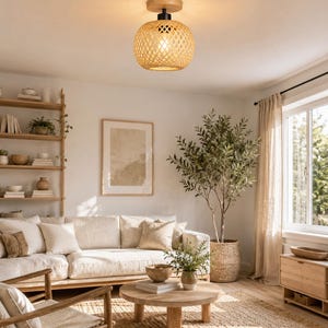 May include: A ceiling light fitting featuring a spherical shade crafted from woven light-coloured bamboo strips. The shade is attached to a circular wooden base with a black metal connector, emitting a warm glow from the internal light bulb.
