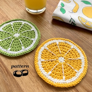 May include: Two crocheted lemon slice coasters, one green and one yellow, with white stitching. The coasters are on a wooden surface. The word "pattern" is written below the coasters.