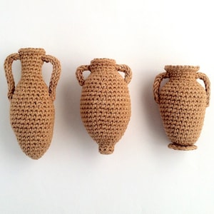 Miniature crocheted amphorae in three different styles.