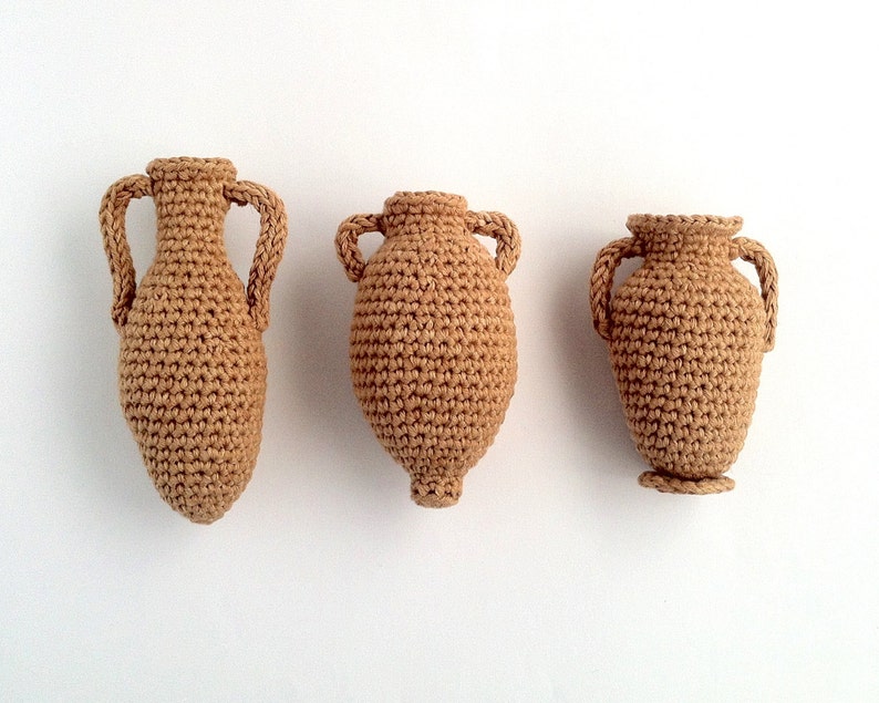 Miniature crocheted amphorae in three different styles.