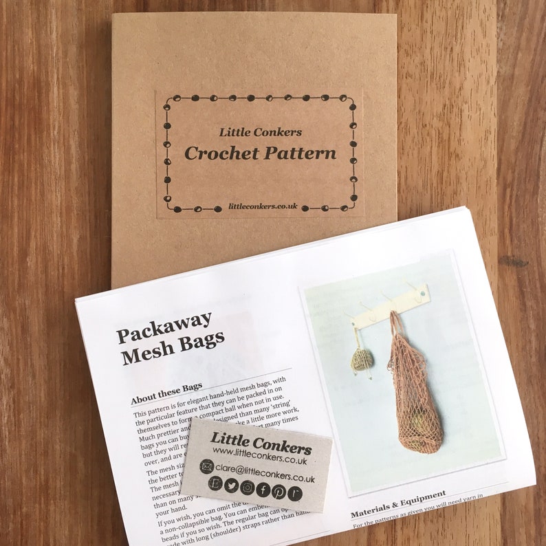 May include: A brown paper folder labeled Little Conkers Crochet Pattern with a website address, accompanied by a white instruction booklet titled Packaway Mesh Bags featuring a photo of a crocheted bag and a small business card with contact details.
