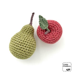 May include: A handmade crochet pear in olive green with a brown stem and a crochet apple in deep pink with a green leaf. The items feature a textured yarn stitch pattern. A small logo in the corner displays the text Little Conkers.