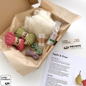 May include: A craft kit in a cardboard box containing white wool stuffing, two skeins of pink and green yarn, two smaller bundles of green and purple yarn, a metal needle, a 3.50 mm bamboo crochet hook, and an Apple & Pear instruction sheet.