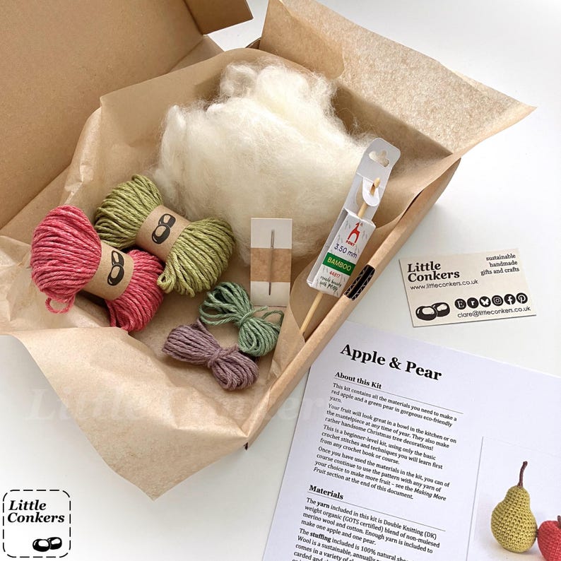 May include: A craft kit in a cardboard box containing white wool stuffing, two skeins of pink and green yarn, two smaller bundles of green and purple yarn, a metal needle, a 3.50 mm bamboo crochet hook, and an Apple & Pear instruction sheet.