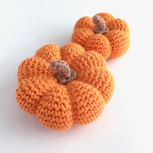 Two crocheted orange mini pumpkins