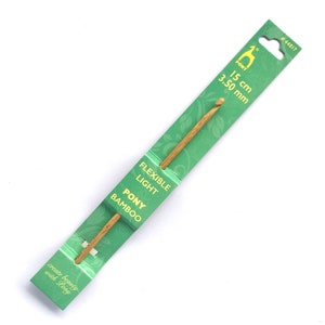 May include: A light brown bamboo crochet hook measuring 15 cm in length and 3.50 mm in diameter, secured to a green cardboard display card. The packaging features the text Pony, Flexible Light, Pony Bamboo, 15 cm, 3.50 mm, #44817, and create beauty with Pony.