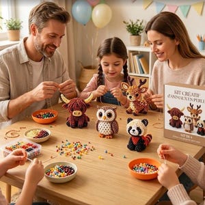 Peut inclure: Un coffret de loisirs créatifs intitulé KIT CRÉATIF d'ANIMAUX EN PERLES comprenant quatre figurines d'animaux en perles : une vache highland brune, un hibou brun, un cerf brun et un panda noir et blanc, avec des perles colorées dans des bols.