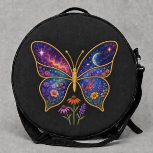 May include: A round black crossbody bag featuring a central embroidered butterfly design. The butterfly wings contain a vibrant galaxy print with stars and a moon, transitioning into colorful floral patterns. Three small flowers sit below.
