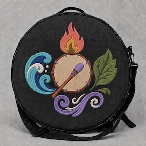May include: A round black bag featuring an embroidered design of a central tan drum with a purple mallet, surrounded by four elemental symbols: a pink and orange flame, a blue wave, a green leaf, and a purple swirling wind pattern.