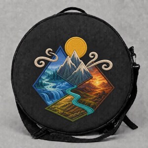 以下が含まれることがあります： 中央にダイヤモンド型の風景刺繍が施された、丸い黒色のショルダーバッグ。刺繍には、雪を頂いた山々、明るい黄色の太陽、流れる青い川、緑豊かな丘、そして渦巻く雲が浮かぶ夕焼けの空が描かれています。