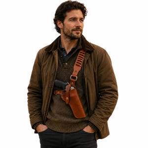 Könnte beinhalten: Eine braune Canvas-Jacke mit dunkelbraunem Cordkragen über einem dunkelbraunen Strickpullover. Ein beigefarbenes Schulterholster aus Leder enthält eine schwarze Handfeuerwaffe, und der Riemen ist mit einer Reihe messingfarbener Patronen besetzt.