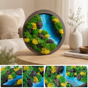 May include: A circular wall art piece featuring a dark brown frame, preserved green and yellow moss, dark grey textured rocks, and a central blue resin river effect. The composition mimics a natural landscape with varied moss textures.