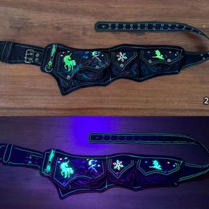 May include: A black utility belt featuring multiple pockets and an adjustable strap with a metal buckle. The belt is decorated with embroidered designs of a unicorn, a crescent moon, stars, and a dragon that glow under ultraviolet light.