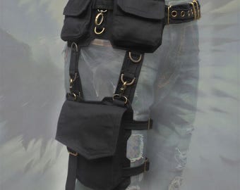 May include: A black utility belt with two upper pouches and a larger lower pouch attached by straps. The belt features brass-colored metal hardware, including D-rings, buckles, and eyelets. The design includes adjustable straps and flaps on each pouch.