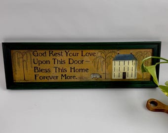 May include: A rectangular wall sign in a dark green frame featuring a tan background with the text God Rest Your Love Upon This Door Bless This Home Forever More. The illustration includes a white house, a small sheep, and willow trees.