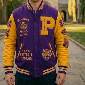 Può includere: Una giacca varsity viola e gialla con una grande lettera P, un grafico di una tigre e testo ricamato tra cui University Varsity Set 1946 e Class of Football Captain. Le maniche sono gialle con polsini a righe e toppe numerate.