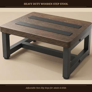 May include: A heavy duty wooden step stool with a dark brown wood grain top and two black non-slip strips. The frame is constructed from black metal with visible side bolts. The text HEAVY DUTY WOODEN STEP STOOL and Adjustable Non-Slip Steps for Adults & Kids is visible.