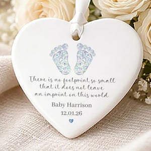 May include: White ceramic heart-shaped ornament with a ribbon. Decorated with baby footprints and the inscription: "There is no footprint so small that it does not leave an imprint on this world." Includes a name and date.