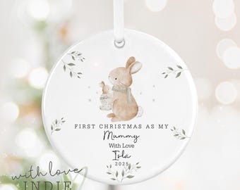 Könnte beinhalten: Runder, weißer Weihnachtsschmuck mit einer Aquarellillustration von zwei Hasen. Der Text lautet "First Christmas as my Mummy, With Love, Isla, 2025." Der Schmuck hat ein weißes Band zum Aufhängen. Der Text "with love INDIE PERSONALIZED GIFTS" steht unten.