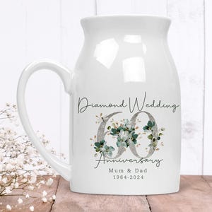 May include: White ceramic mug with a handle, featuring a floral design and the text "Diamond Wedding 60 Anniversary Mum & Dad 1964-2024".