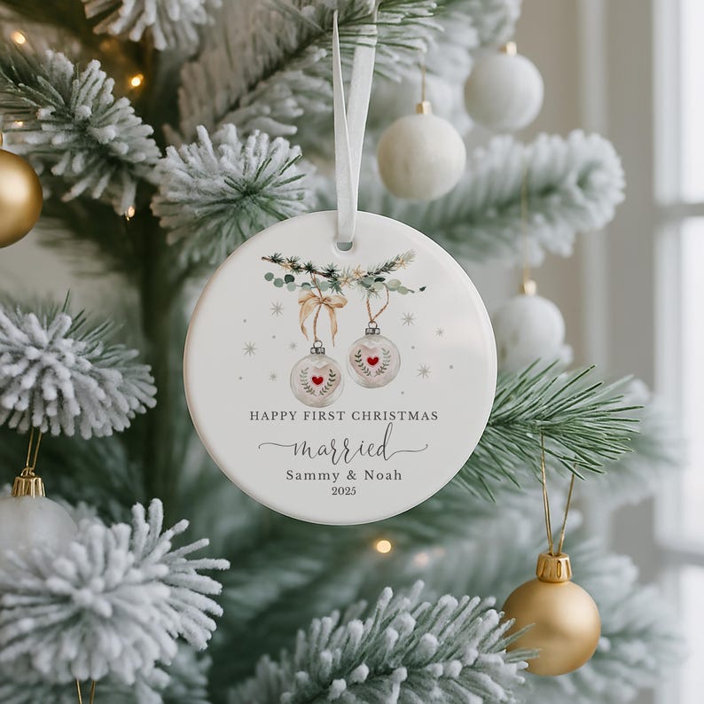 Round white ceramic ornament hanging on a snowy artificial Christmas tree.