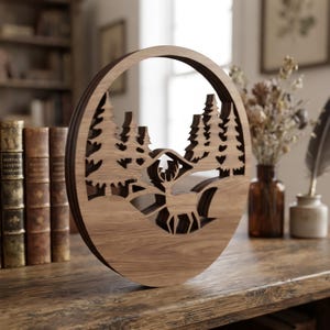May include: A circular wooden wall art piece featuring a laser-cut layered design of a forest landscape with pine trees and a standing deer. The natural wood grain is visible throughout the structure, which displays depth through its stacked layers.
