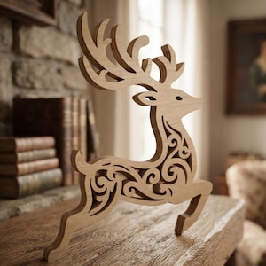 May include: A light-colored wooden deer figurine featuring intricate, laser-cut scrollwork patterns throughout its body and large, branching antlers. The object is crafted from layered wood, displaying a natural grain texture and a smooth finish.